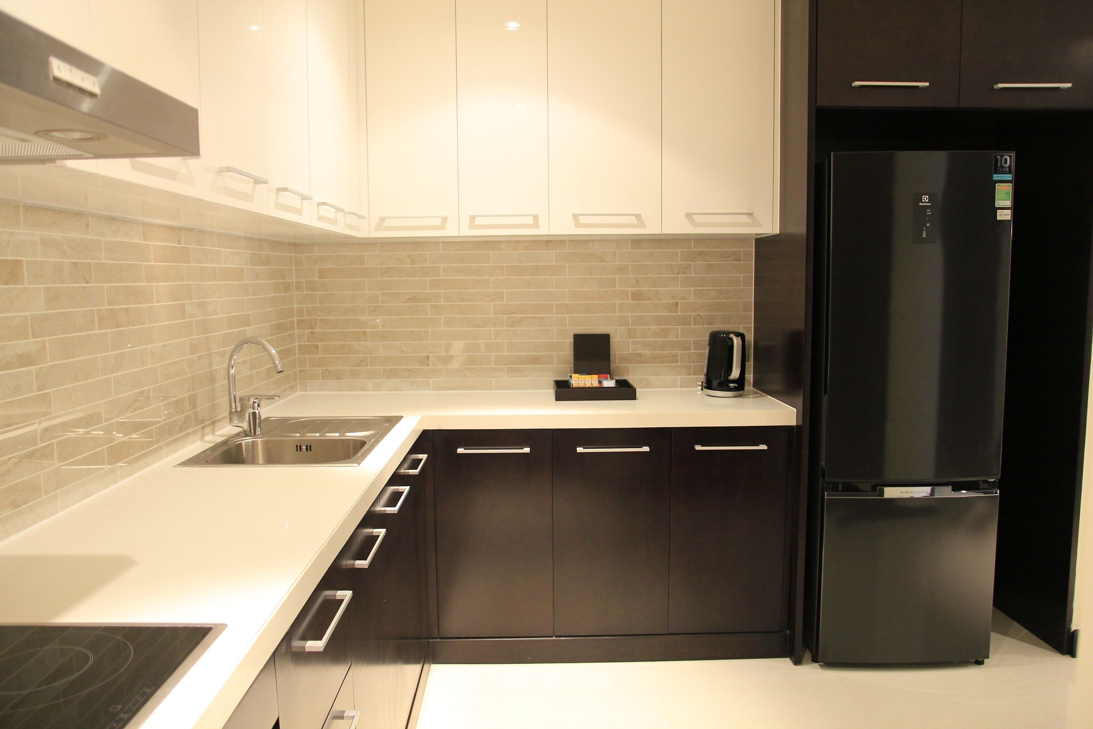 A modern kitchen with a built-in stove, a sink, and a black refrigerator.