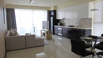 A modern kitchen with white cabinets, a dining table with chairs, and a sofa in a living area.