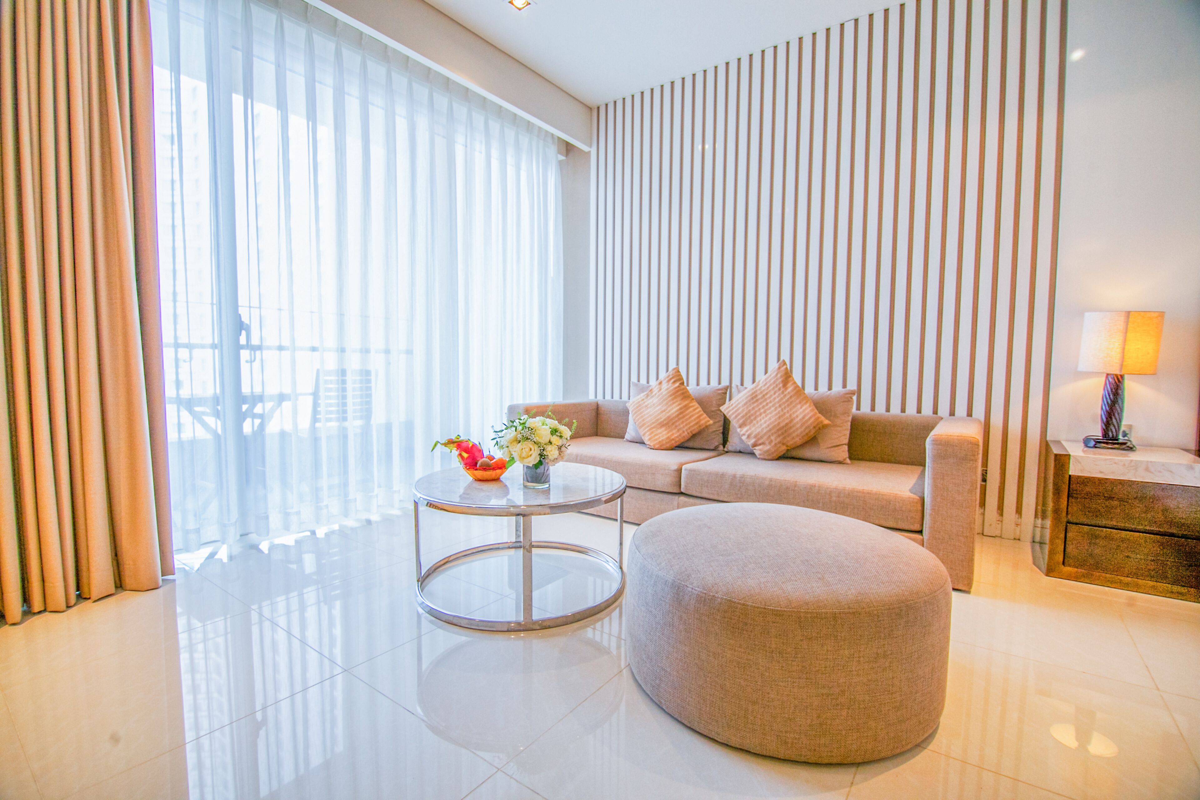 A modern living room with a sofa, ottoman, and round coffee table.
