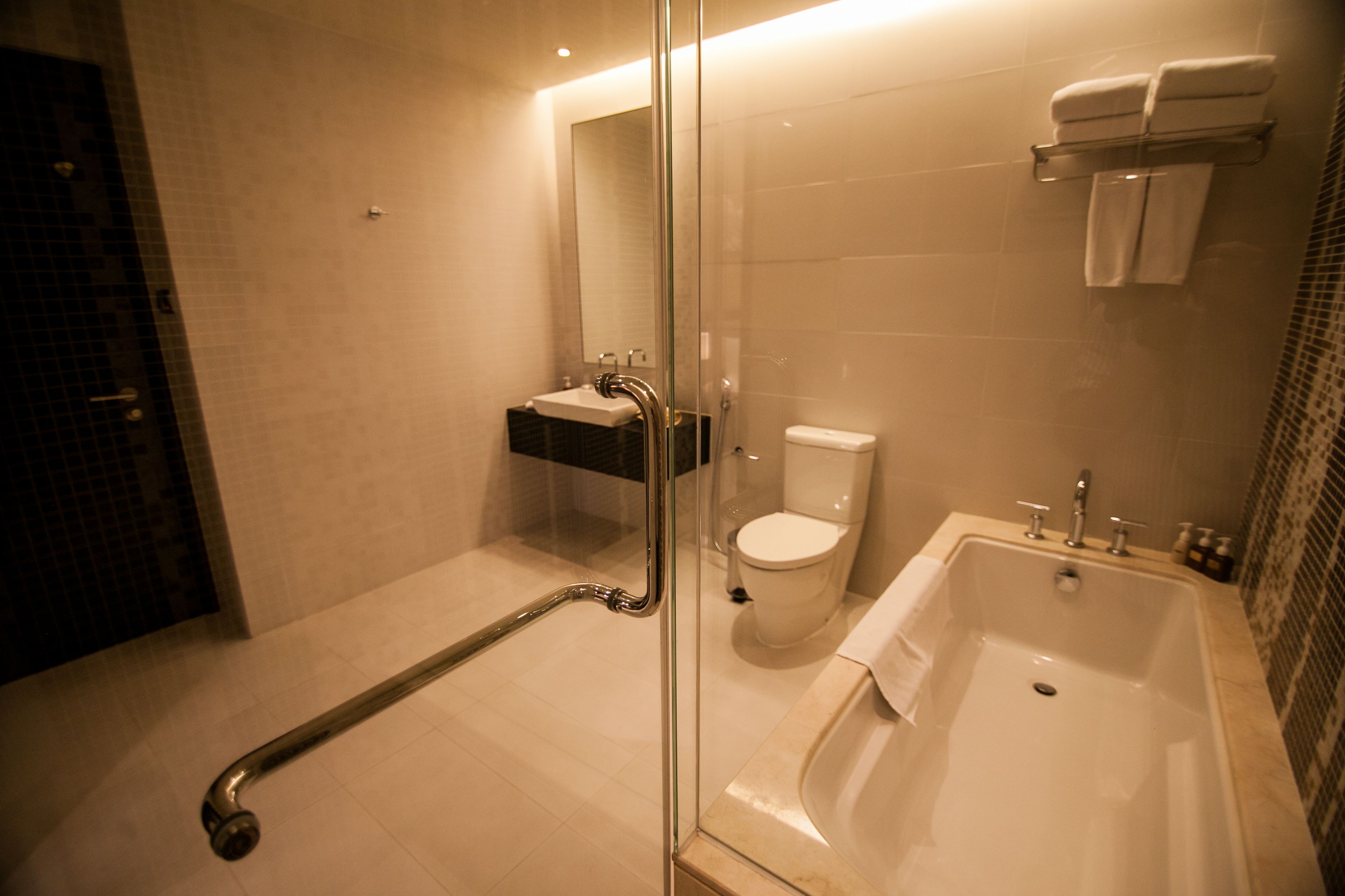A modern bathroom with a glass shower enclosure, a white bathtub, and a toilet.
