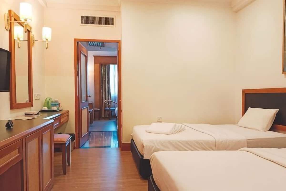 A hotel room with two beds, a desk with a chair, a mirror, and a television.