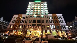 Un hotel de varios pisos con ventanas iluminadas y un letrero verde en la parte superior.