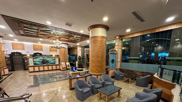 Un vestíbulo con piso de mármol, mostrador de recepción, zona de estar y un gran ventanal con vistas.