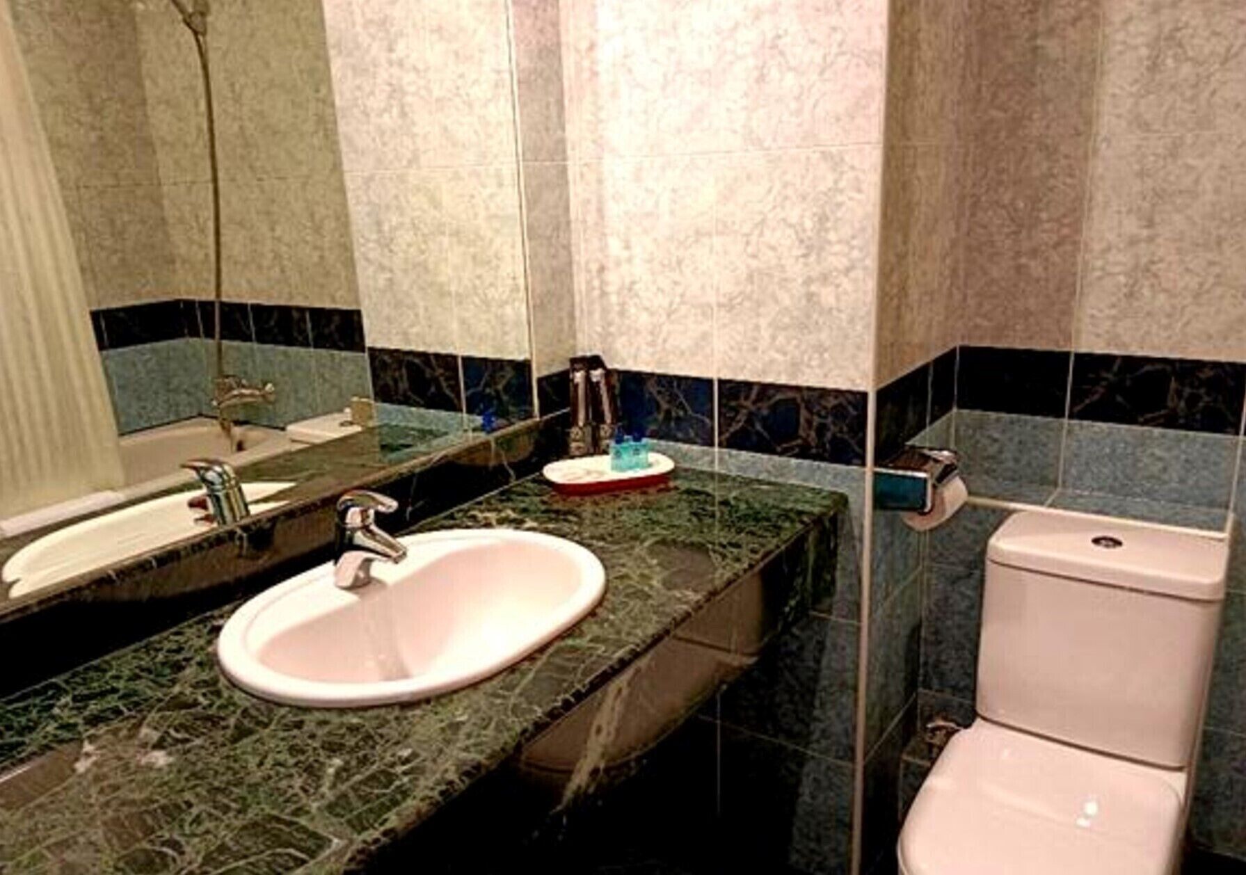 A bathroom with a sink, mirror, and toilet.