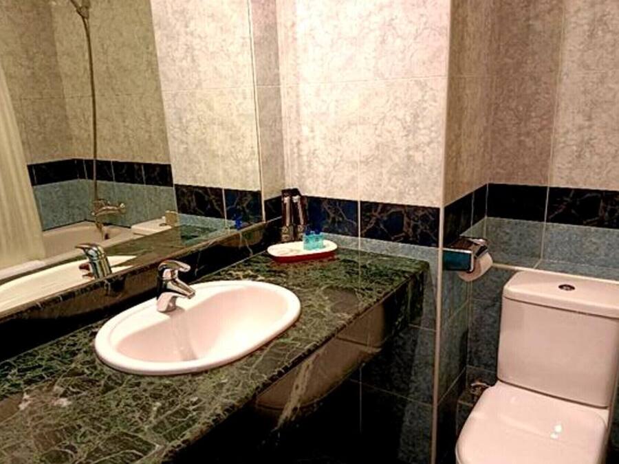 A bathroom with a sink, mirror, and toilet.