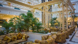 A luxurious lobby with ornate furniture, a glass ceiling, and lush greenery. - Rixos Khadisha Shymkent (Shymkent)