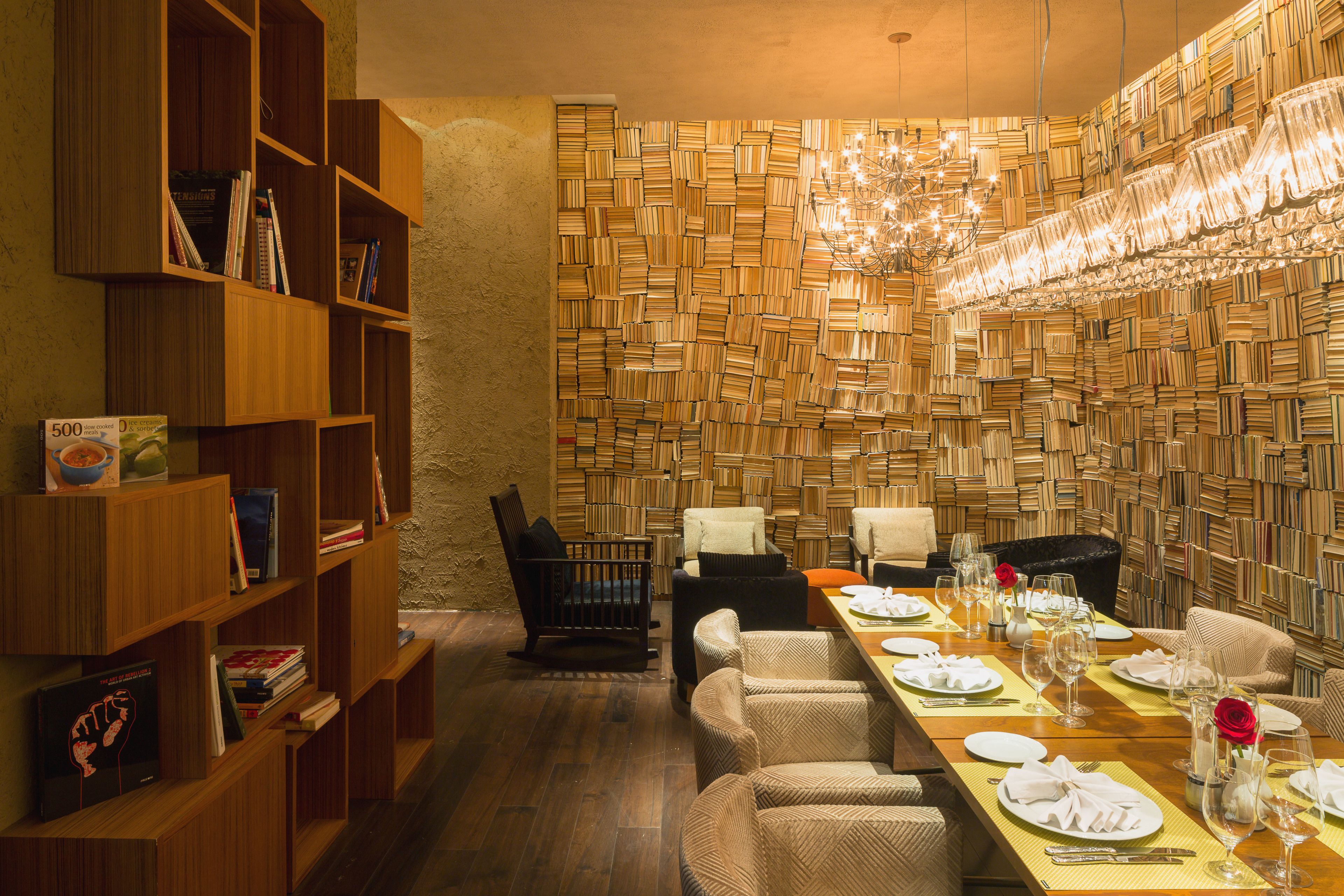 A dining area with a long table set for a meal, surrounded by bookshelves and a wall of books.