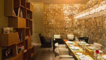 A dining area with a long table set for a meal, surrounded by bookshelves and a wall of books.