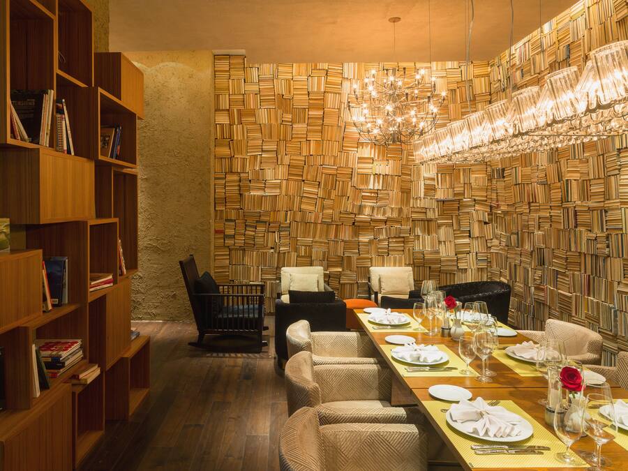 A dining area with a long table set for a meal, surrounded by bookshelves and a wall of books.