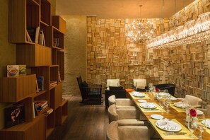A dining area with a long table set for a meal, surrounded by bookshelves and a wall of books.