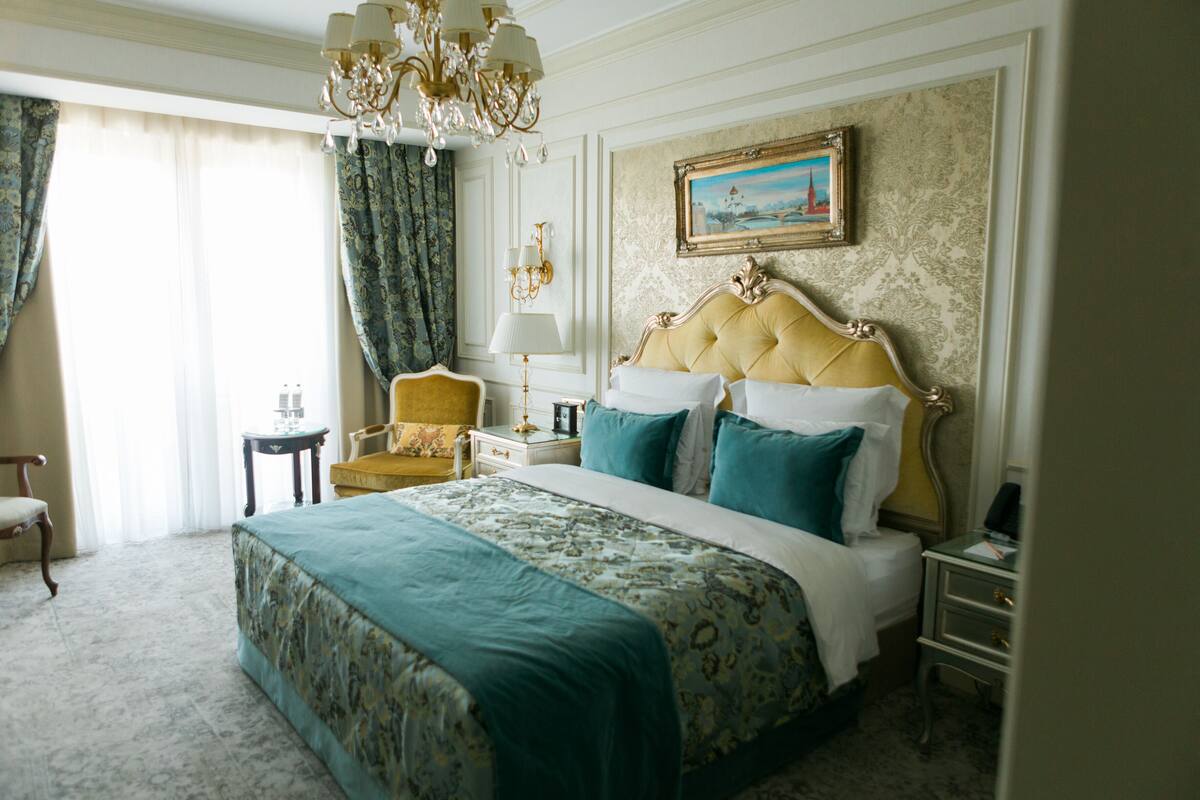A spacious bedroom with a large bed, a nightstand, a chair, and a chandelier.