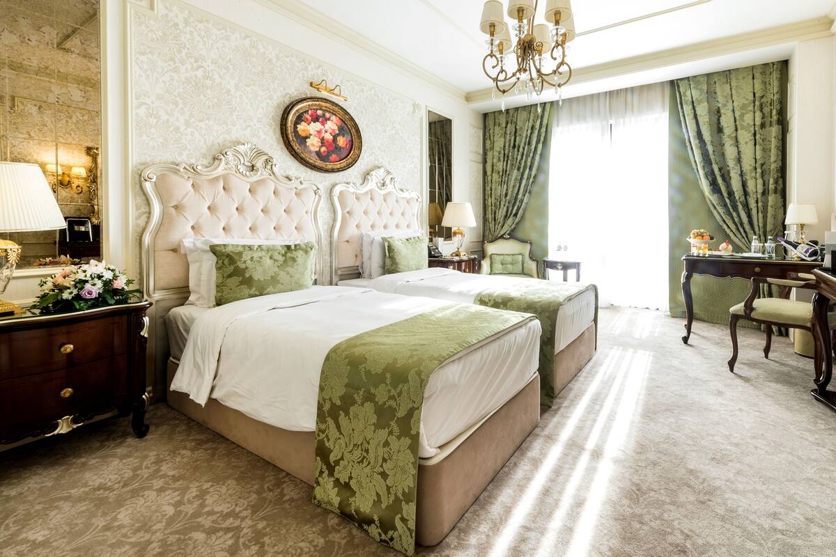 A hotel bedroom with a large bed, two bedside tables, a dresser, and a desk with a chair.