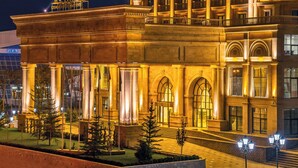 A grand hotel with classical architecture, featuring large columns, arched windows, and a well-lit facade. - Rixos Khadisha Shymkent (Shymkent)