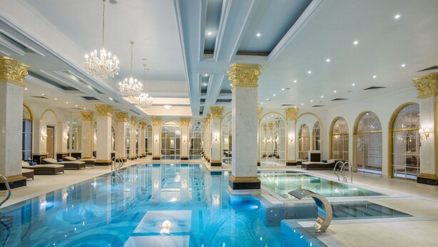 A large indoor swimming pool with multiple lanes, surrounded by columns and arches, and equipped with modern lighting fixtures. - Rixos Khadisha Shymkent (Shymkent)