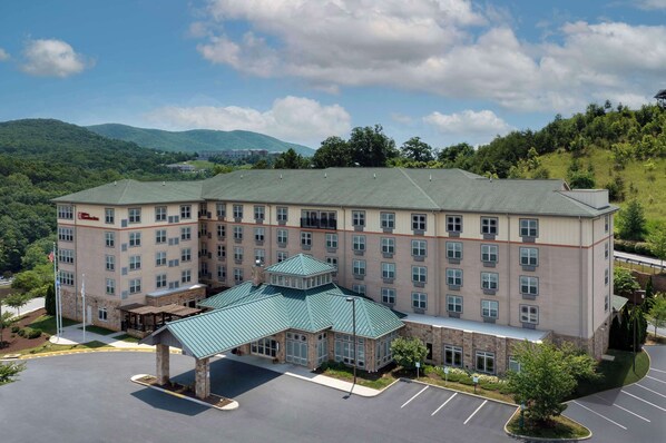 A multi-story hotel with a central courtyard, large windows, and a green roof.