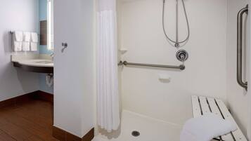 A bathroom with a shower, a bench, and a towel rack.