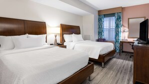 A hotel room with two beds, a desk, a chair, a TV, and a window with curtains. - Hilton Garden Inn Roanoke (Roanoke)
