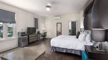 Een hotelkamer met een bed, bureau, stoel, televisie en een grote spiegel.