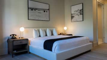 A neatly arranged hotel room with a large bed, two bedside tables with lamps, and two framed pictures on the walls.
