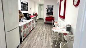 A modern kitchen with white cabinets, a wooden floor, and a dining area with a red table and chairs. - Relais Cola di Rienzo (Rome)