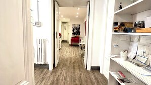 A hallway with wooden flooring, white walls, and a red-framed mirror. There are shelves with various items and a radiator on the left. - Relais Cola di Rienzo (Rome)