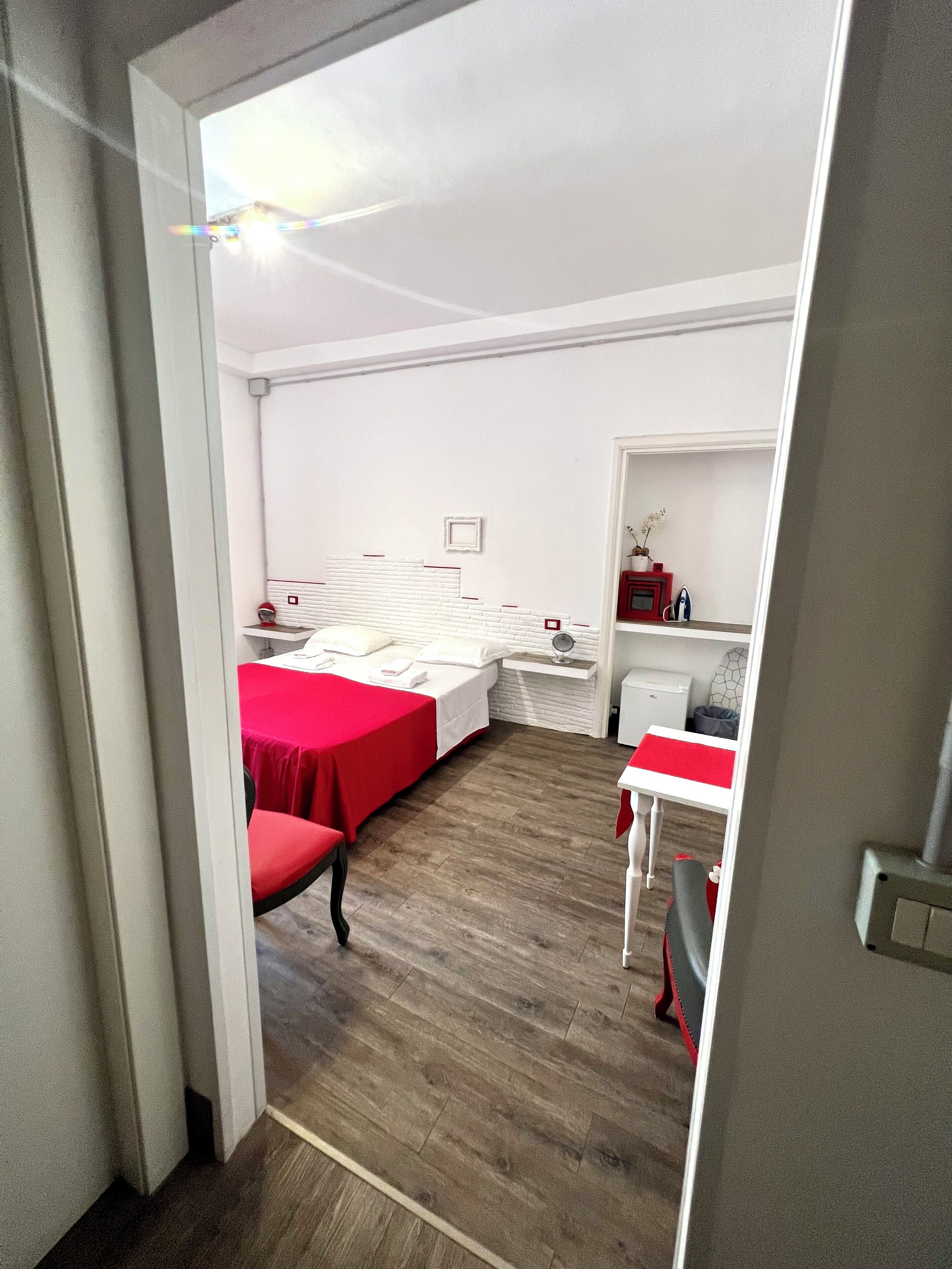 Quarto de hotel com cama, escrivaninha, cadeira e mesa pequena.