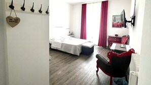 A hotel room with a bed, a desk, and a chair. There is a coat rack with hooks and a heart-shaped sign. - Relais Cola di Rienzo (Rome)