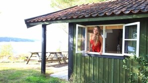 Una cabaña de madera con techo de tejas, una ventana y una mesa de picnic al fondo.