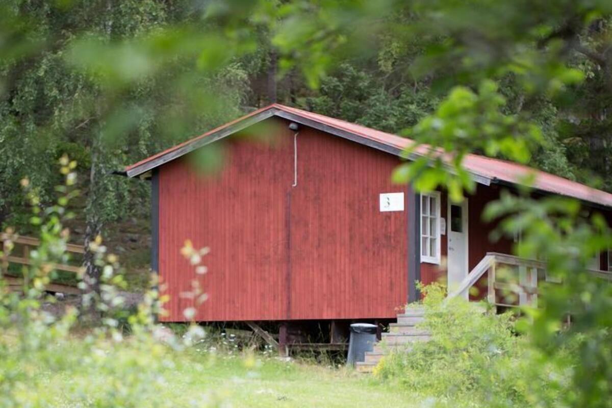 A red wooden cabin with a small porch and steps leading up to the door.