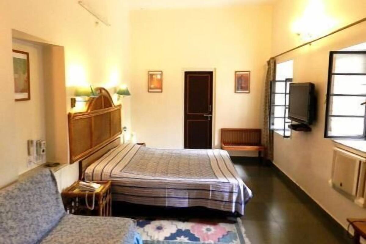 Ein Hotelzimmer mit einem Bett, einer Couch, einem Fernseher und einer Tür.
