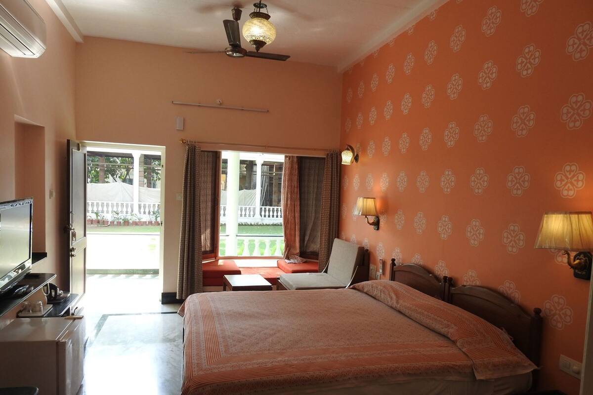 Ein Hotelzimmer mit Bett, Schreibtisch, Fernseher, Deckenventilator und Blick nach draußen.