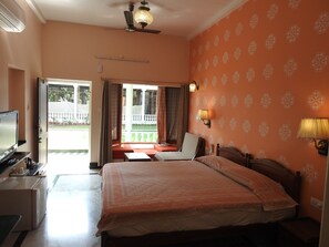 Une chambre d’hôtel équipée d’un lit, d’une télévision, d’un bureau et d’un balcon avec vue sur l’extérieur.