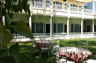 A courtyard with a white balcony, green lawn, and outdoor furniture.