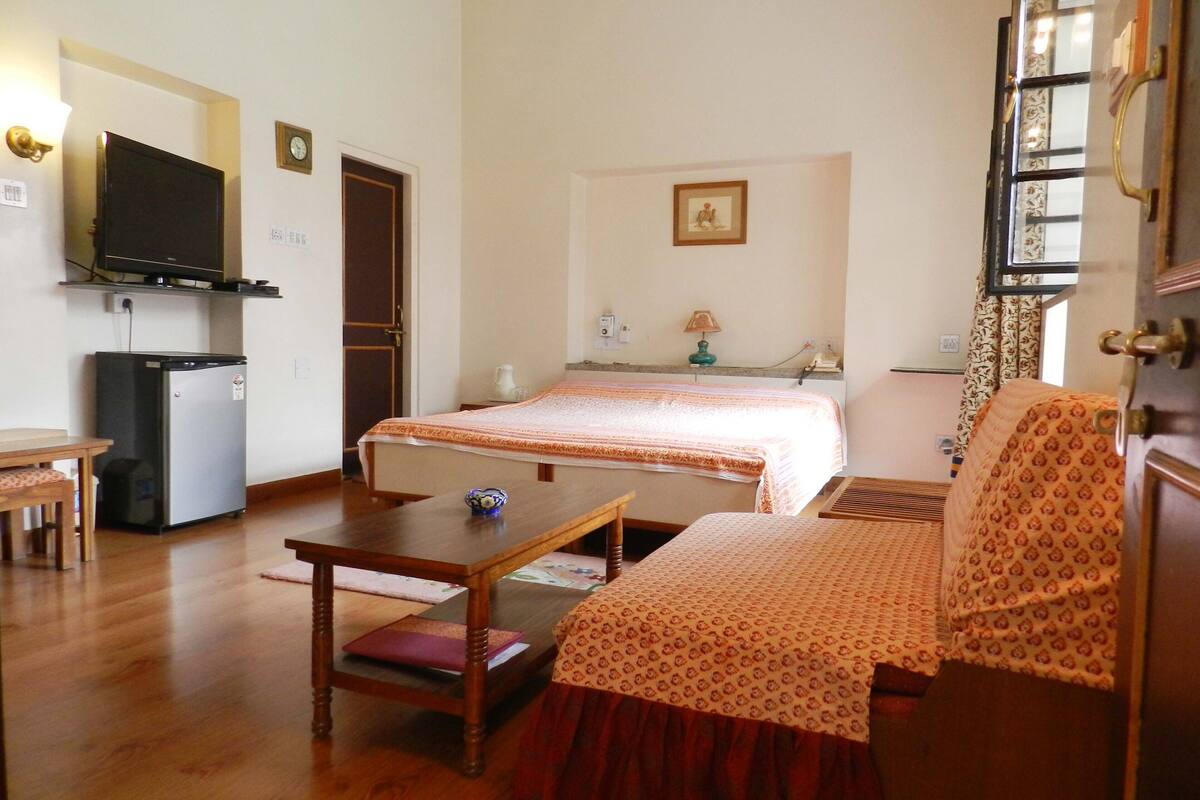 Ein Hotelzimmer mit Bett, Schreibtisch, Stuhl, Fernseher und Kühlschrank.
