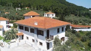 A white building with a red-tiled roof, multiple windows, and a balcony. - Hotel Ariadne (Skopelos)