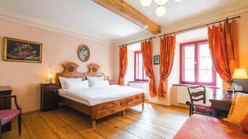 A bedroom with a wooden bed, a nightstand, a chair, a window with curtains, and a wall clock.