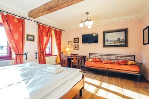 Un dormitorio con cama, escritorio, silla, televisor y un cuadro en la pared.
