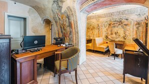Quarto com escrivaninha de madeira, um laptop HP, cadeira listrada, piano e um mural na parede.