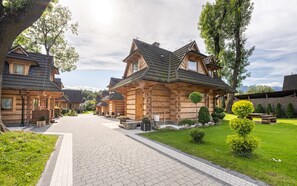 Fileira de edifícios no estilo de cabanas de toras, com um passeio pavimentado e gramados bem cuidados.