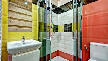 Ein Badezimmer mit einer Duschkabine, einem weißen Waschbecken und einer roten Toilette.