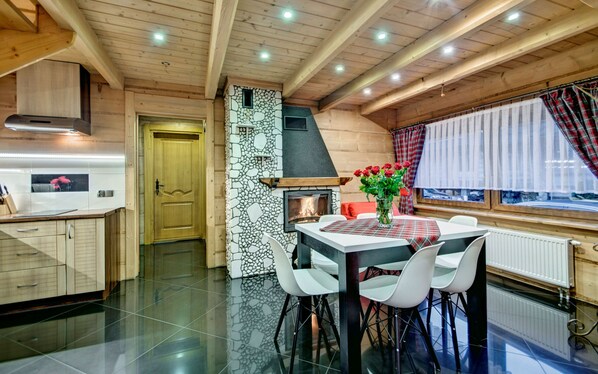 Una cocina moderna con pared de piedra, chimenea y zona de comedor con mesa y sillas.