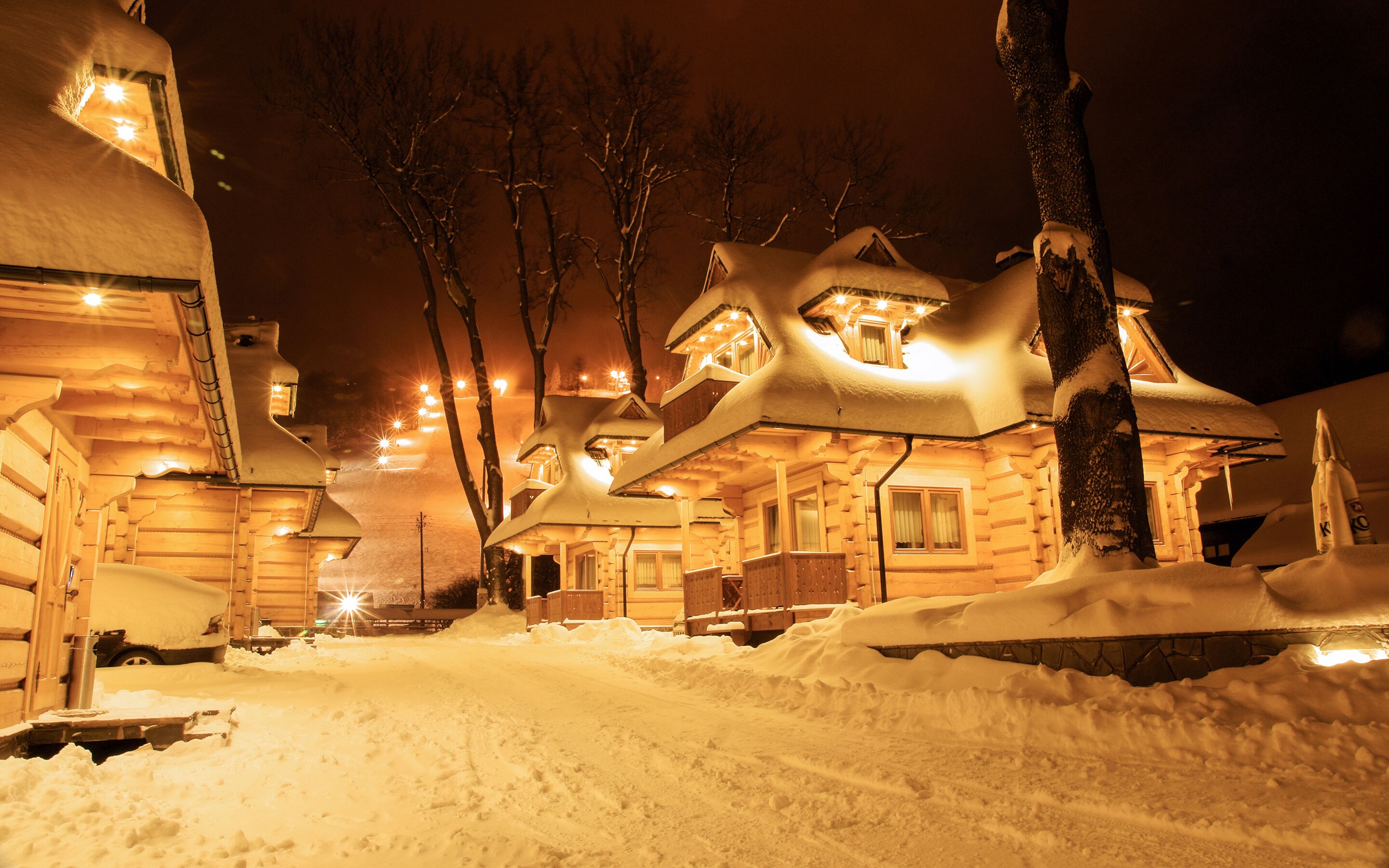 A log cabin with multiple rooms, a snow-covered driveway, and a rocket model in the foreground.