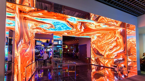 A modern interior with a reflective floor and a vibrant, abstract wall design. - The LINQ Hotel & Casino – A Caesars Rewards Destination (Las Vegas)