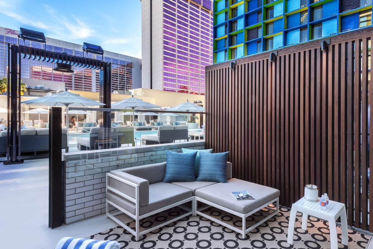 A modern outdoor lounge area with a sofa, a small table, and a pool view.