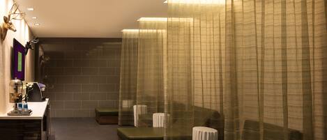 A spa room with a massage table, a small reception desk, and a wall-mounted mirror.