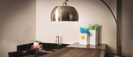 A modern kitchen with a wooden dining table, a stainless steel sink, and a pendant light.