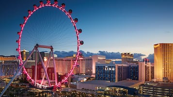 A Ferris wheel with a cityscape in the background, including The LINQ hotel and other buildings.