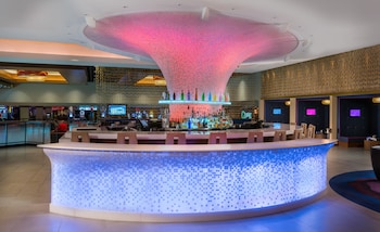 A bar area with a long counter, multiple stools, and a brick wall backdrop. at The LINQ Hotel & Casino – A Caesars Rewards Destination