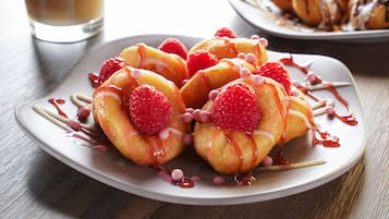 A plate of pastries with raspberries and drizzled syrup.