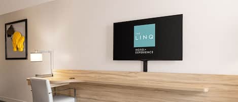 Un comptoir d’accueil d’hôtel au design moderne, une œuvre d’art encadrée au mur et une enseigne indiquant « The LINQ Hotel+ Experience ».